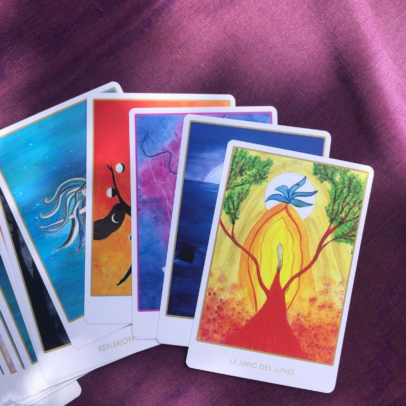 Cartes Révelle étalées sur un tissus, illustration avec les peintures originales de Lorina invitant à la connexion avec la sagesse intérieure et le corps.