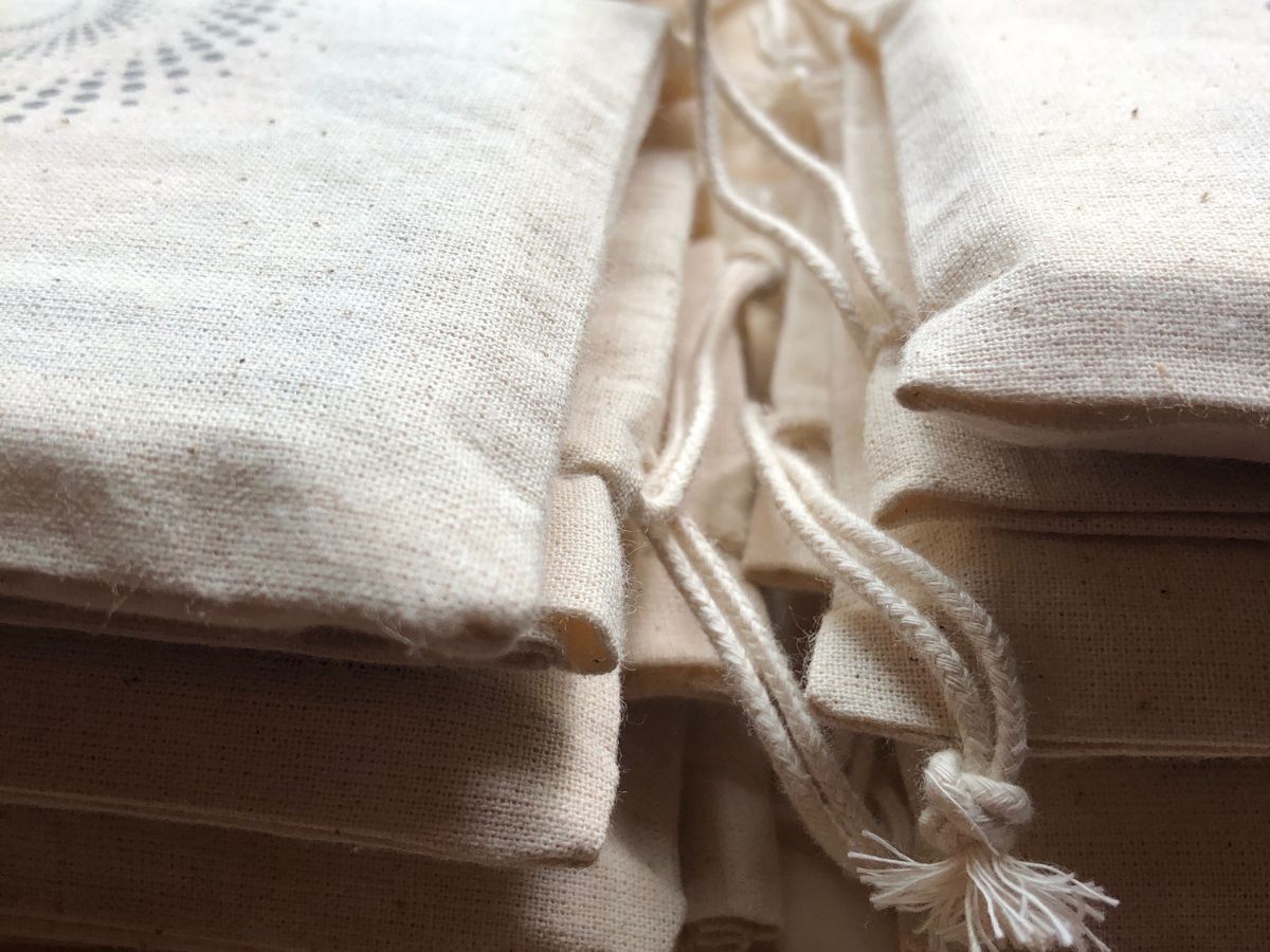 Plusieurs pochettes en coton contenant les Cartes Révelle de Lorina, outil de transmission et de beauté pour les femmes, fabriqué avec soin.